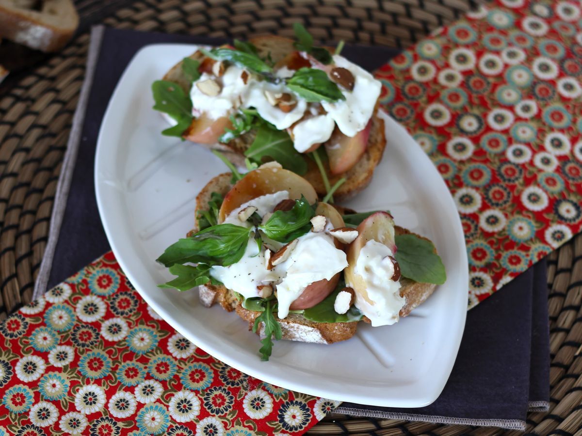 Rucola, rostade persikor och burrata på rostat bröd: en supergod kombination av sött och salt!